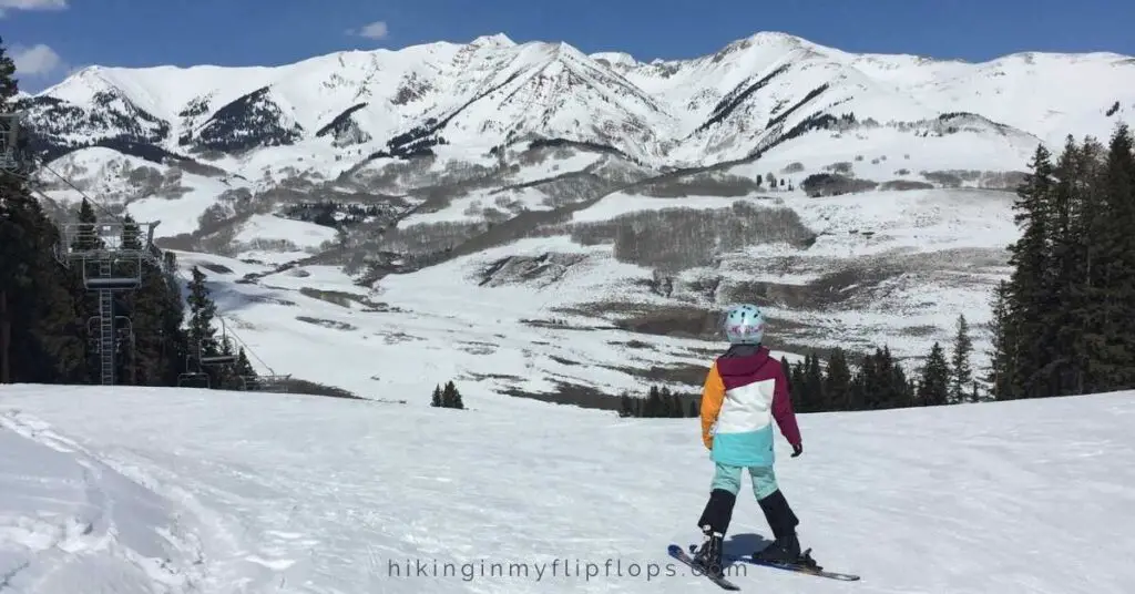 a girl at the top of a ski run depicting first-time skiing tips