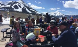 the family having lunch at a picnic table on a mountain at a ski resort