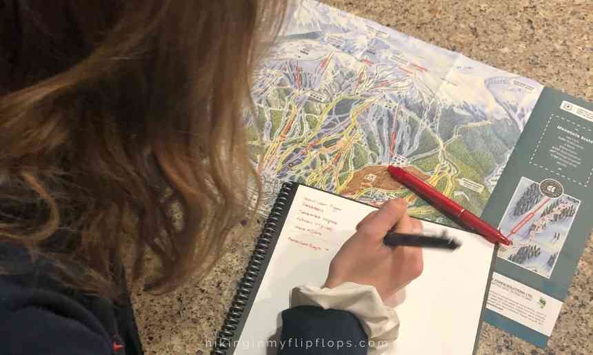 a girl making notes while looking at a ski area map