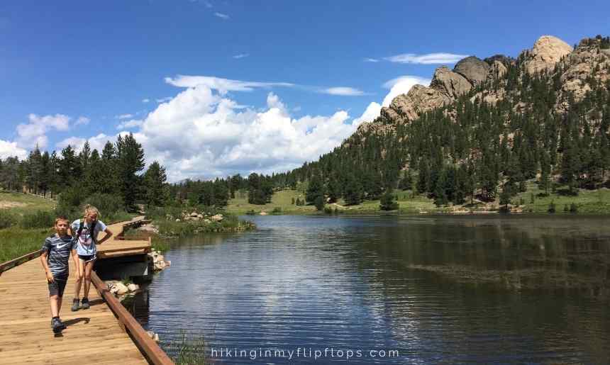 kids walking a boardwalk hiking trail around a lake depicting tips for hiking with kids