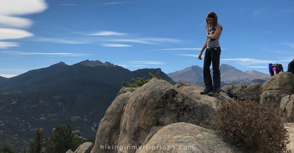 a girl on top of a rocky summit with views of the Rocky Mountains on Kruger Rock Trail