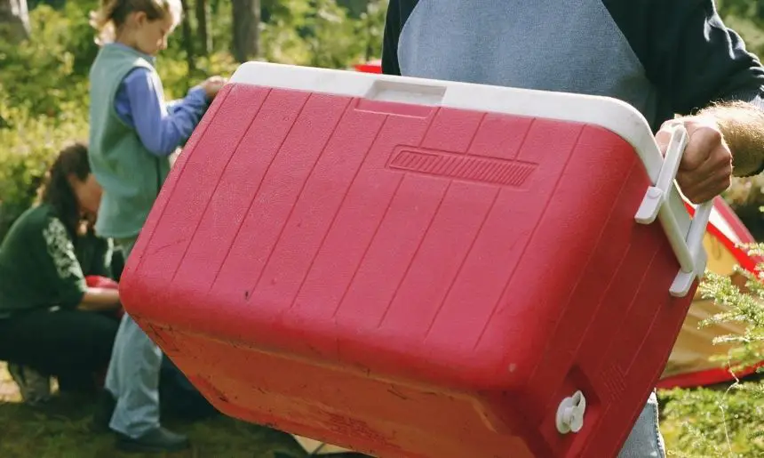 a man carrying a cooler, depicting how to make ice last longer in a cooler