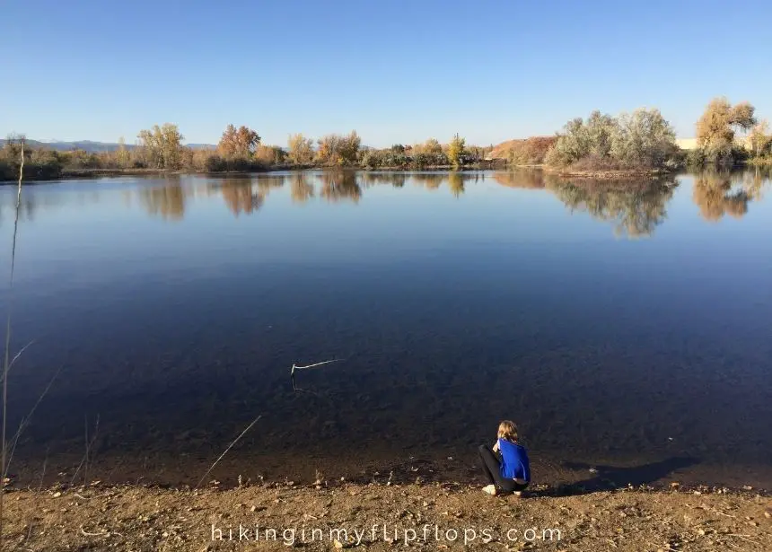 a girl at the water's edge at Sawhill Ponds, one of the best hiking trails in Boulder for kids