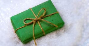 a gift wrapped in green paper sitting on fluffy white snow