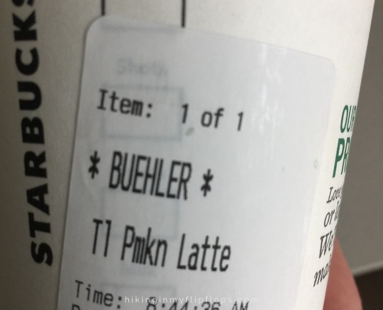 a Starbucks cup with the name "Buehler" depicting one of the Cotopaxi Questival challenges