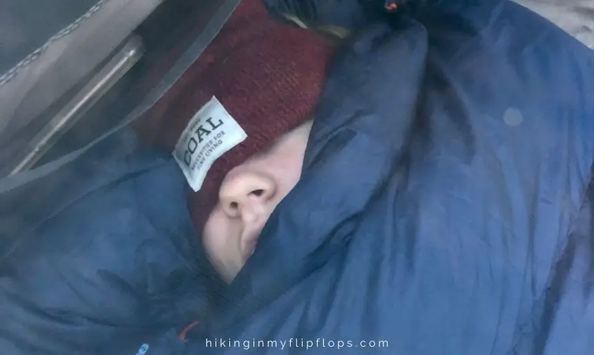 tips for cold weather camping include wearing a beanie when snuggled in your sleeping bag