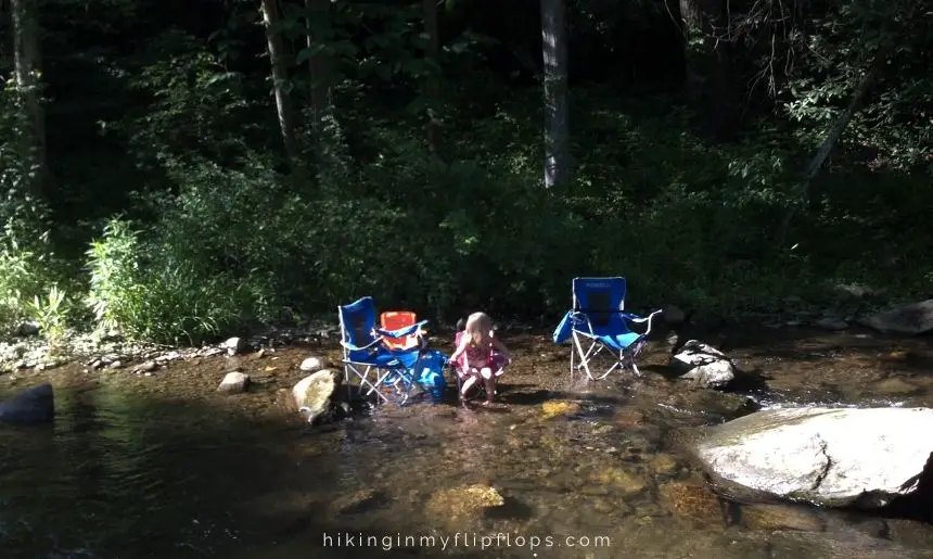 a girl sitting in a camp chair in a creek, how to stay cool while camping