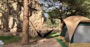 a camper relaxing in a hammock near a tent