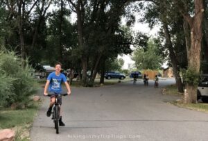 a boy riding his bike on the roads through a campground