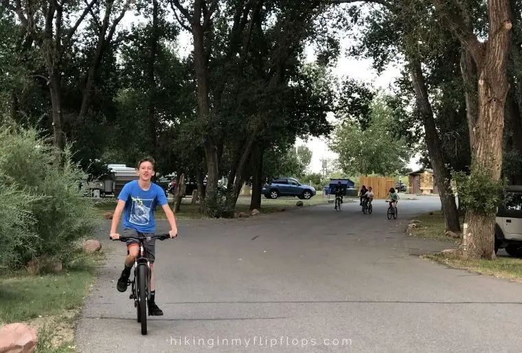 a boy riding a bike on the roads of a campground, showing one of the fun things to do while camping