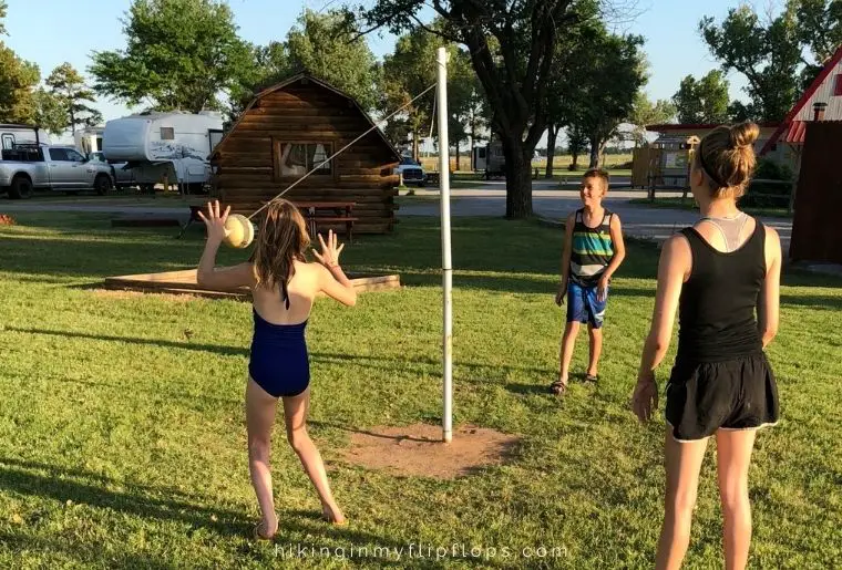 three kids playing tetherball at a campground