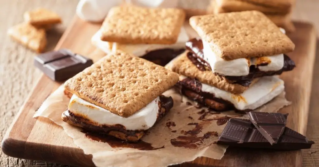 a wooden serving board with assembled s'mores depicting one of the s'mores ideas for camping