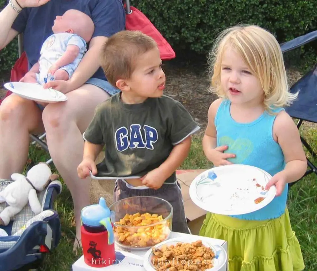 young kids having a road trip snack during a break from driving