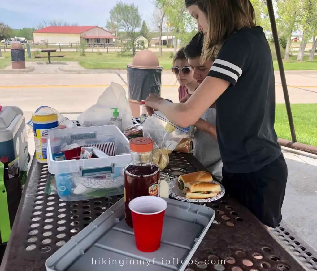 a rest stop picnic table where a family is having a road trip meal