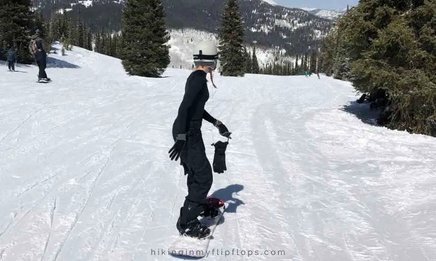 a snowboarder wearing gloves with a leash, which is a feature of the best snowboarding gloves