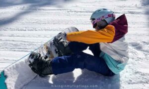 a snowboarder getting strapped in, a snowboard phrase for locking a boot into the binding