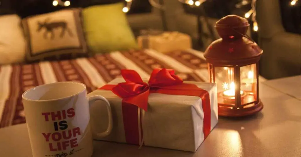 a wrapped gift displayed with a lantern in a camper van representing the best camping gifts