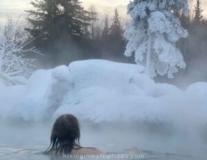 a girl soaking in the warm waters of a hot spring in Alaska, one of the best Fairbanks winter activities