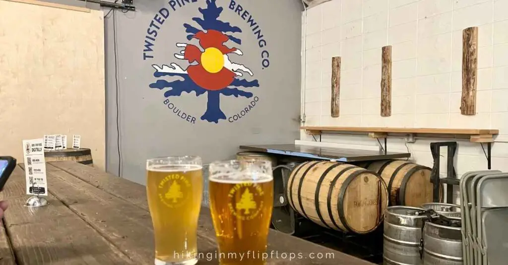 two pints of beer with the Twisted Pine logo in the background depicting the best breweries in Boulder CO