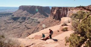 kids sitting on the rocky red terrain to take in views at Canyonlands NP