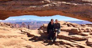 two people sitting in front of Mesa Arch at Canyonlands NP