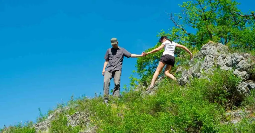 a couple getting down a steep trail together showing the  physical contact of a hiking date 