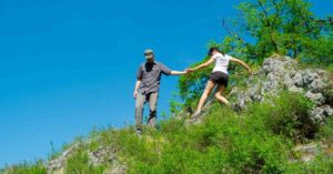 a couple getting down a steep trail together showing the physical contact of a hiking date