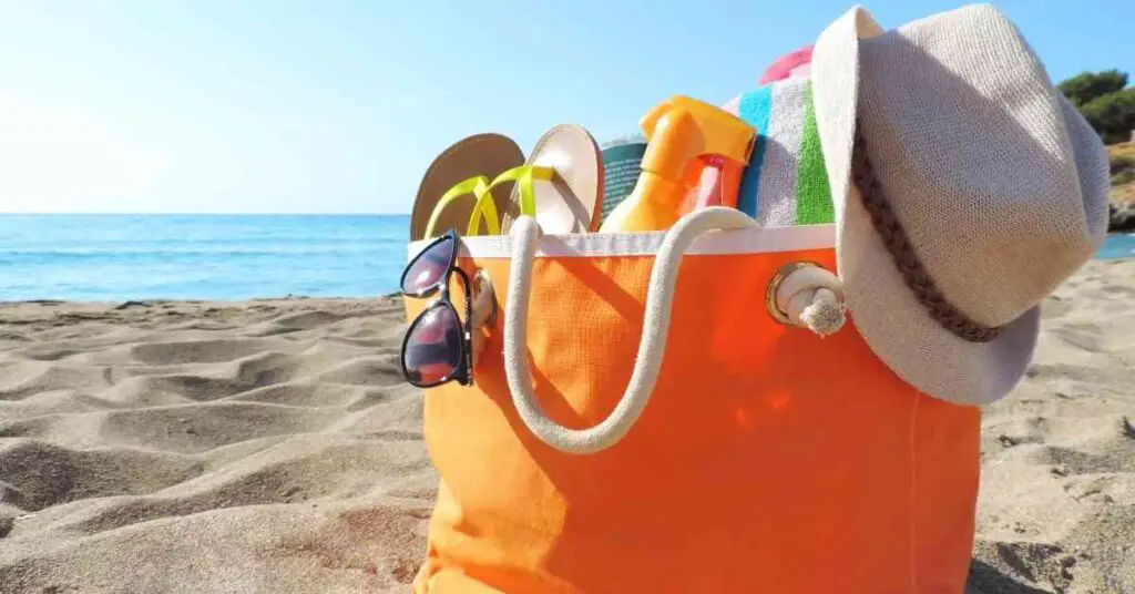 a beach bag sitting in the sand depicting best beach and pool bags for moms