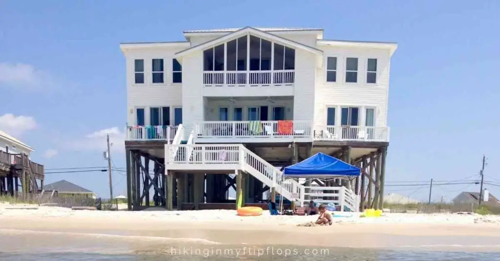 a boy playing in the sand in front of a beach house shows items on a family beach trip packing list