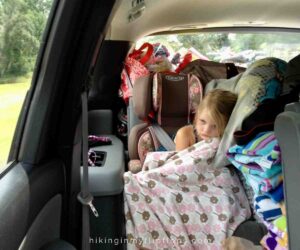 a girl in the car with her favorite blanket showing family road trip essentials