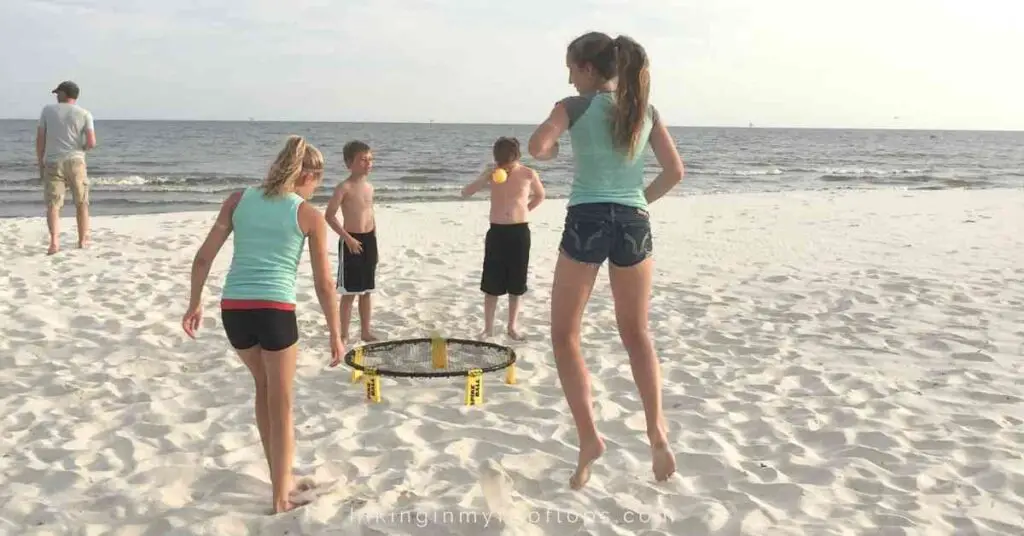 kids playing spikeball on a beach