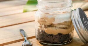 a mason jar with chocolate cake, pudding, and bananas showing the best make-ahead camping desserts