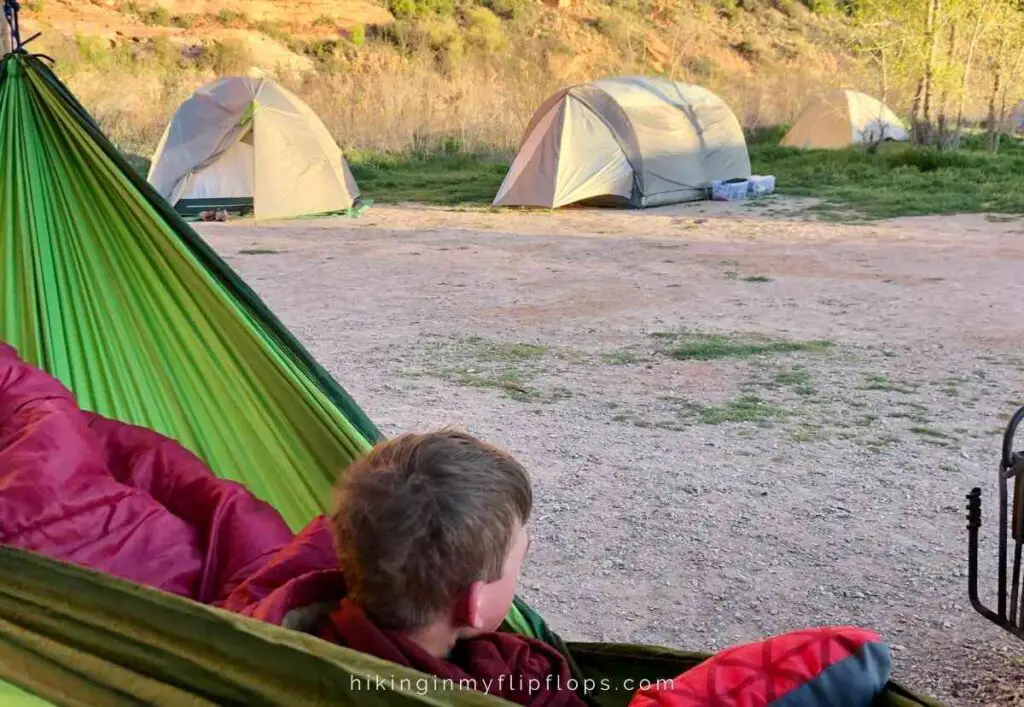 a teen sleeping in a hammock at a campground shows how to make camping with teens a success