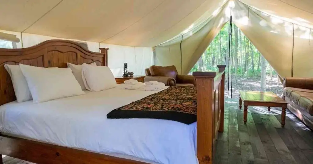 a bed, armchair, and sofa inside of a glamping tent depict what to bring glamping
