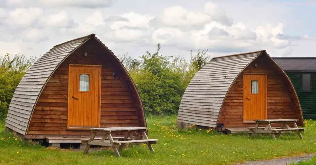 two glamping cabins shown in a grassy field