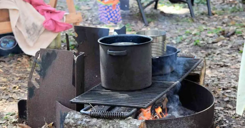 pots on a grill grate over a campfire