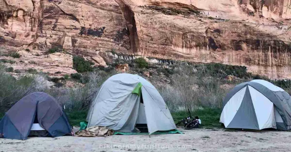 three camping tents set up in front of a canyon wall depict camping without electricity