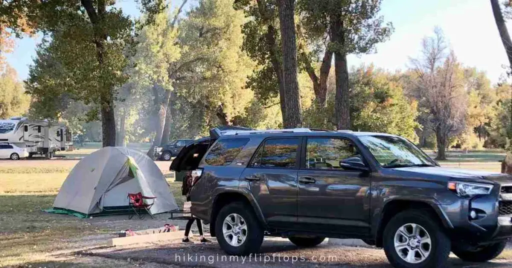 an SUV by a tent set up at a campground