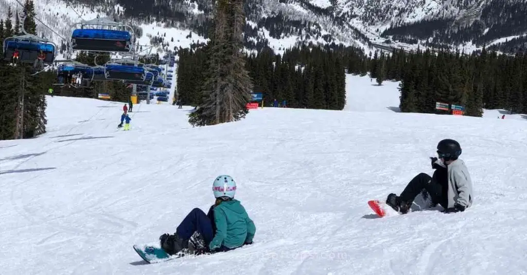 two kids on snowboards getting ready for the run